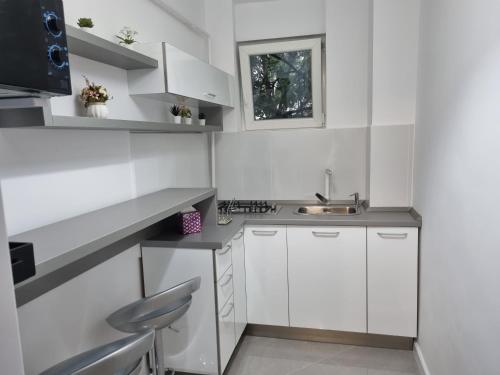 una cocina blanca con armarios blancos y fregadero en Apartament QUIET en Galaţi