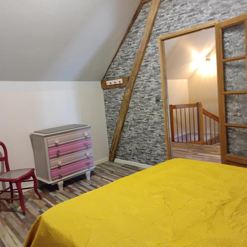 - une chambre avec un lit jaune et un mur en briques dans l'établissement La coquette, à Bué