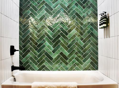 a bathroom with a tub and a green tiled wall at Glenwood Pines in Flagstaff