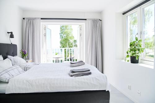 a white bedroom with two beds and a window at Lotsvillan in Höllviken
