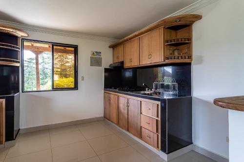 a kitchen with wooden cabinets and black appliances at Soy Local Guatape Campestre in Guatapé