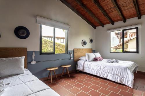 a bedroom with two beds and two windows at Soy Local Guatape Campestre in Guatapé