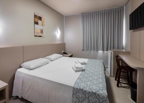 Habitación de hotel con cama y escritorio en Hotel Pitol en Balneario Camboriú