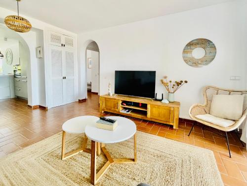 ein Wohnzimmer mit einem TV und einem Tisch in der Unterkunft La Terraza de la Sabina in Es Mercadal
