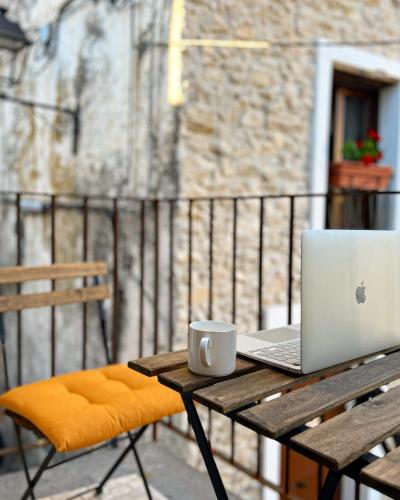 a laptop computer sitting on a wooden table with a coffee cup at La Casa di Nenna in Trentinara