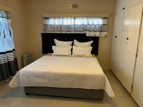 a bedroom with a bed with white sheets and a window at The Big Five Bed and breakfast in Mooirivier