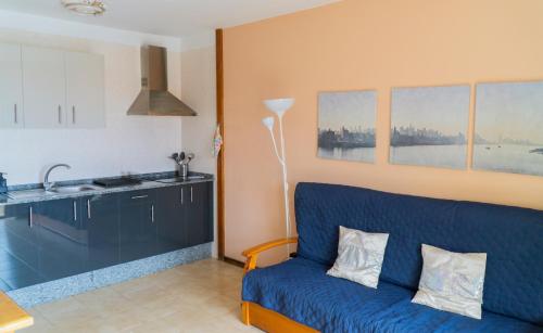 a living room with a blue couch and a kitchen at Apartamentos TAMARAGUA in Breña Baja