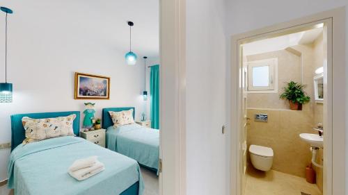 a bedroom with two beds and a bathroom with a sink at Villa Urania Kamilari in Kamilari