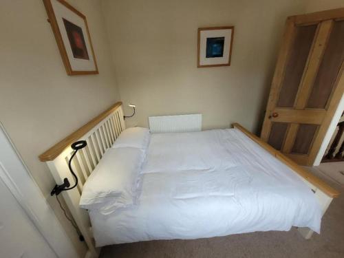 a bedroom with a white bed with a wooden frame at Character cottage in centre of Moffat in Moffat