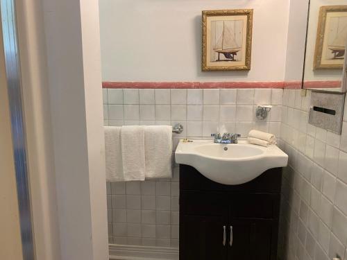 a white bathroom with a sink and a mirror at Hotel Kenney Rideau in Crosby