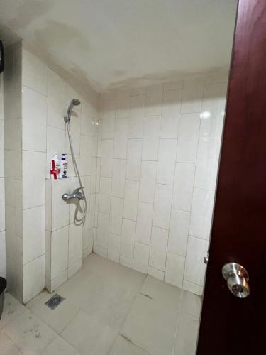 uma casa de banho com um chuveiro com azulejos brancos em Sewa Apartemen Jogja MATARAM CITY em Kejayan