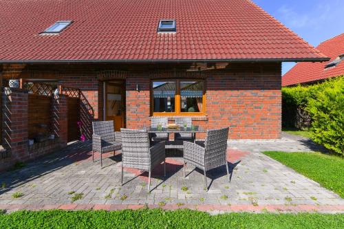 een patio met een tafel en stoelen voor een bakstenen huis bij Ferienwohnungen Haus Meeresleuchten in Bensersiel