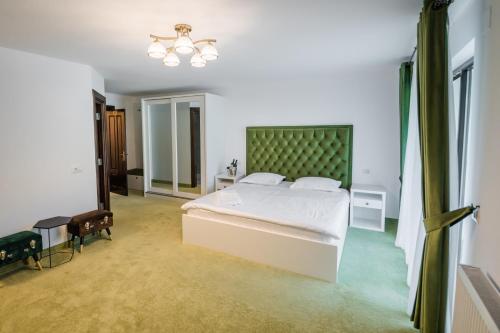 a bedroom with a large white bed with a green headboard at SOMARA in Găineşti