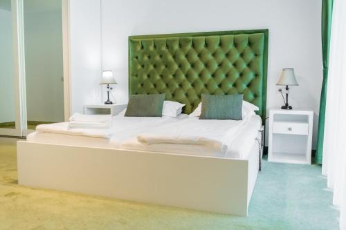 a bedroom with a large bed with a green headboard at SOMARA in Găineşti