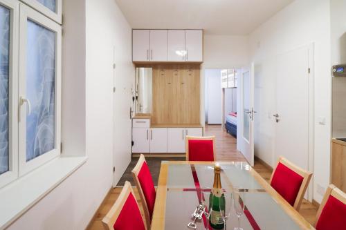 ウィーンにあるCozyNite Premium Apartment Schönbrunn 1のキッチン、ダイニングルーム(ガラステーブル、赤い椅子付)