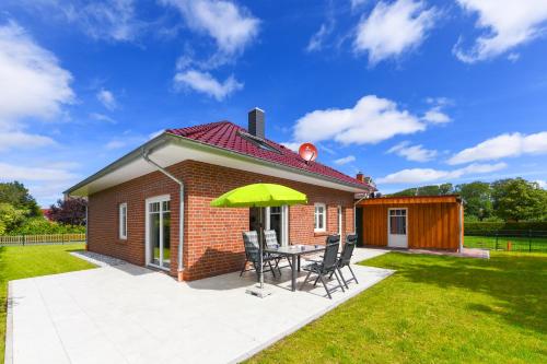 ein kleines Haus mit einem Tisch und einem grünen Sonnenschirm in der Unterkunft Ferienhaus Nordseeperle Neuharlingersiel in Neuharlingersiel