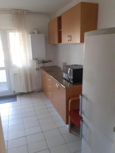 a kitchen with a refrigerator and a white tile floor at Good luck apartament in Mediaş