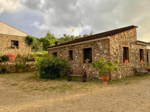 ein Steingebäude mit einer Bank davor in der Unterkunft Finca La Portilla in Aroche
