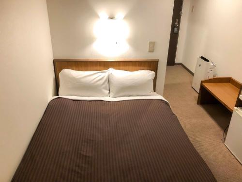 uma cama num quarto com uma luz por cima em City Hotel Air Port in Prince - Vacation STAY 80750v em Izumi-Sano