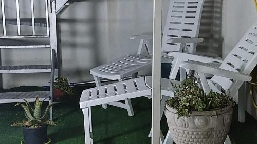 two white chairs and a potted plant on a porch at La Dolce Oasi in Triscina