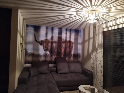 una sala de estar con sofá y una pintura de un toro en Ferienhof-Dachsberg Wohnung Highlander, en Bermatingen