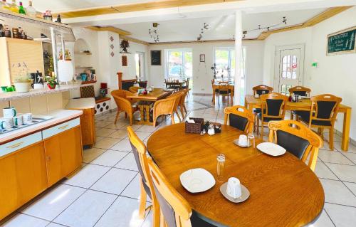 a restaurant with wooden tables and chairs and a kitchen at Vor lauter Bäumen B&B in Zorge