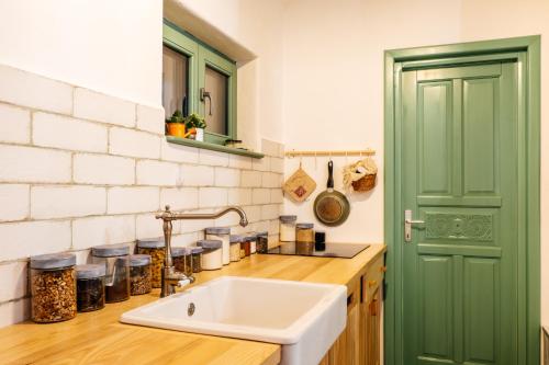 uma cozinha com um lavatório e uma porta verde em Dimineți în Cerdac em Piatra Neamţ