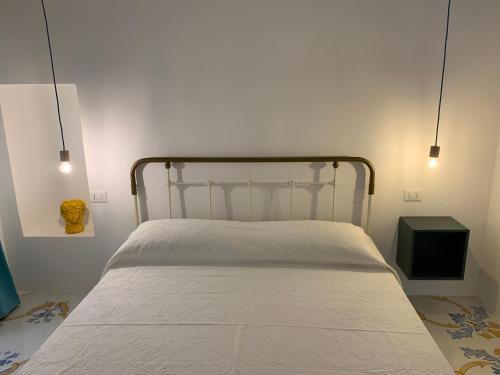 Una cama en un dormitorio con dos luces encima. en Solis Domus Oriens, en Ostuni