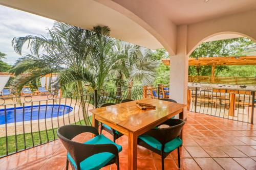 a patio with a table and chairs and a pool at Casa Mimosa in Playa Flamingo