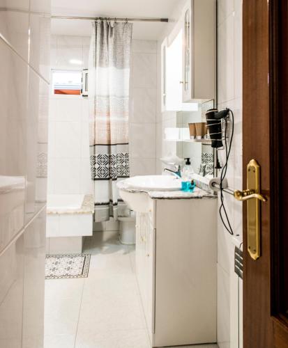 a white bathroom with a sink and a toilet at Las Aceñas De Iris in Sarria