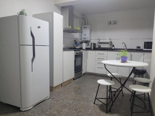 een witte keuken met een tafel en een koelkast bij BE Apartments Vicente in Mendoza