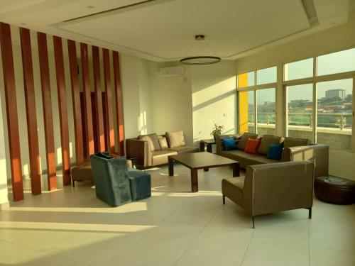 a living room with couches and a table and windows at Penthouse au coeur de Yaoundé Quartier Bastos in Yaoundé