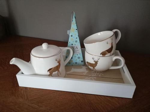 two tea cups and a christmas tree on a shelf at Lesse en Ciel vous accueille avec plaisir . in Houyet