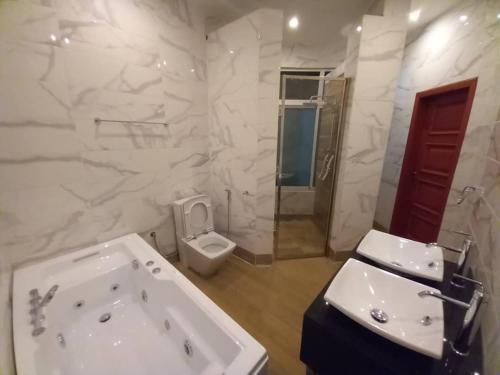 a bathroom with a tub and a sink and a toilet at Penthouse au coeur de Yaoundé Quartier Bastos in Yaoundé