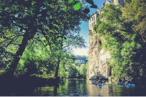 a river with people in a boat on it at Lesse en Ciel vous accueille avec plaisir . in Houyet
