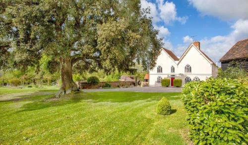 un gran árbol en el patio de una casa blanca en The Farm Exclusive Hire, en Stapleford Tawney