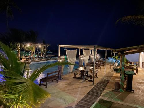 a patio with a table and chairs next to a pool at night at WegoKite Stars in Taíba