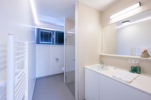 a white bathroom with a sink and a mirror at Modern City Hideaway Graz in Graz