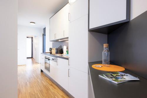a kitchen with white cabinets and a bottle on a counter at Modern City Hideaway Graz in Graz