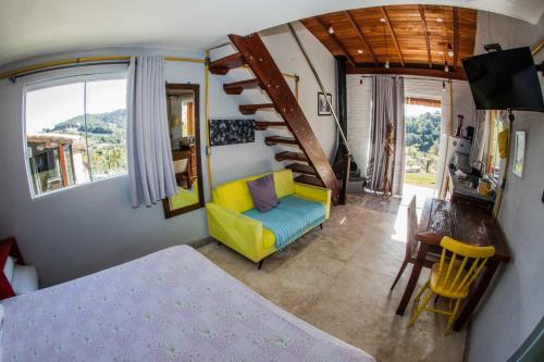 a living room with a yellow couch and a staircase at Chalé vista incrível Monte Alegre Village in Monte Alegre do Sul