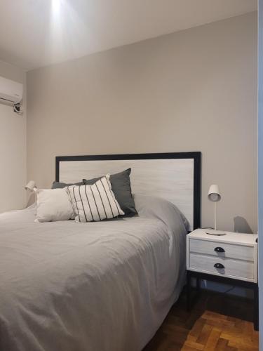 a white bedroom with a bed and a night stand at BE Apartments Vicente in Mendoza