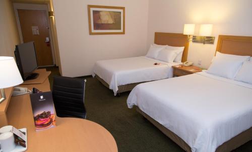 a hotel room with two beds and a desk with a computer at Fiesta Inn Ecatepec in Mexico City