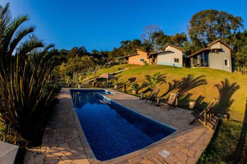 a swimming pool in front of a house at Chalé vista incrível Monte Alegre Village in Monte Alegre do Sul