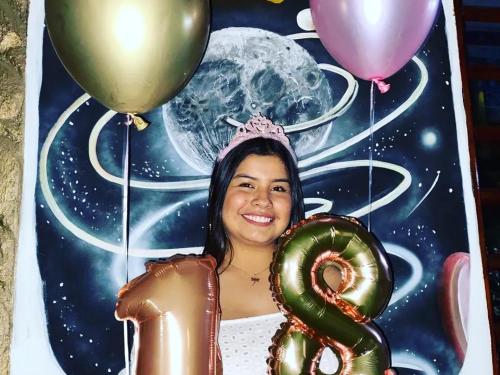 a girl holding a pretzel and balloons in front of a picture at Cabañas Guacari San Agustín huila in San Agustín