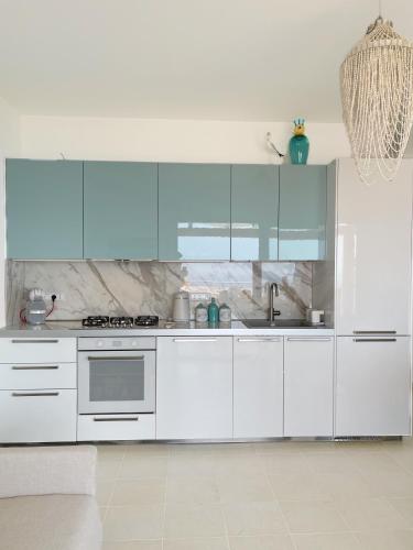 a white kitchen with blue cabinets and a sink at Villa Sofia *Luxury experience in Calabria in Zambrone