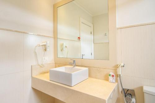 y baño con lavabo blanco y espejo. en Pousada Italia Eleganza, en Campos do Jordão