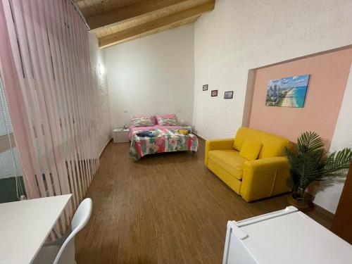 a living room with a yellow chair and a bed at Holiday Home NomiS in Maratea