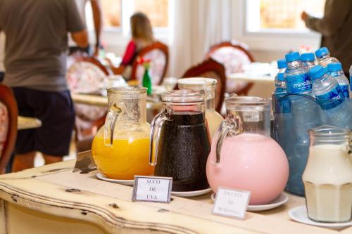 a table with different types of drinks in jars on it at Pousada Italia Eleganza in Campos do Jordão