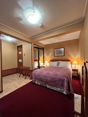 a bedroom with a large bed with a purple blanket at Hotel Mosul in Concepción