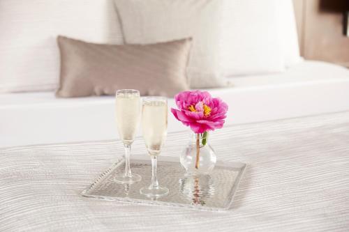 two champagne glasses and a flower in a vase on a bed at The Royal Regency Hotel in Yonkers